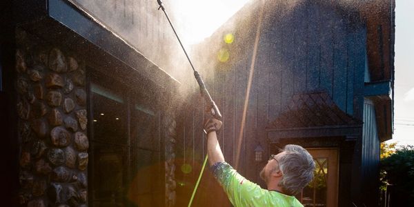Man pressure washing home and windows.