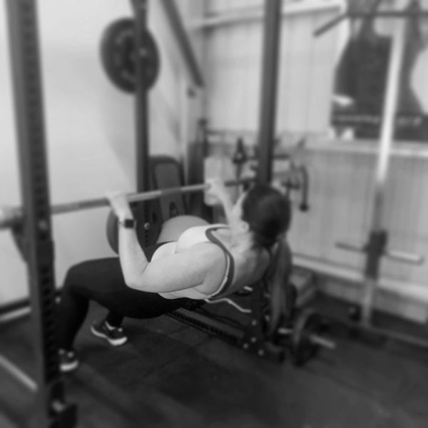 Woman performing inverted row exercise in gym.