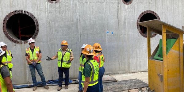 A group of construction workers standing around in front of a wall.