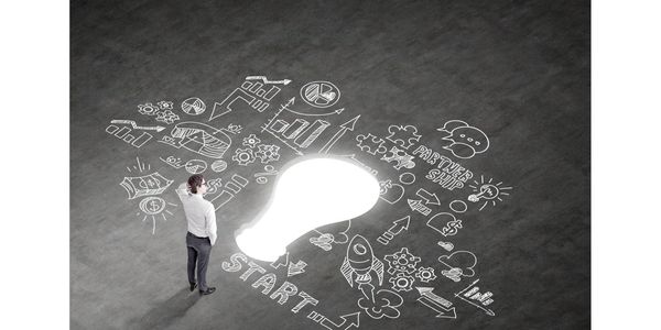 man standing in front of business road map, with a illuminating light bulb in the middle