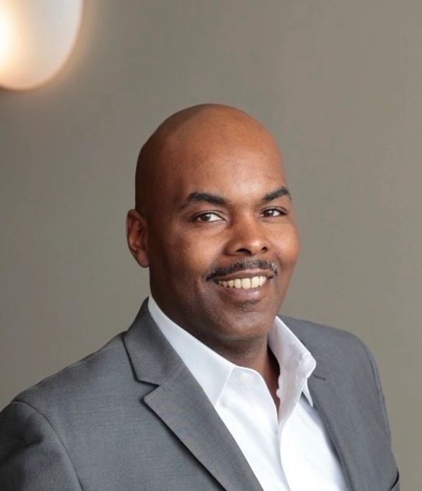 Smiling man in a gray suit with white shirt.