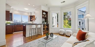 Bright living room connected to a kitchen with city views and modern decor.