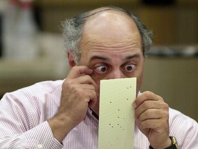 Man examining a perforated card closely.