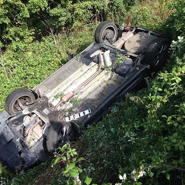 An upturned car laying in a ditch