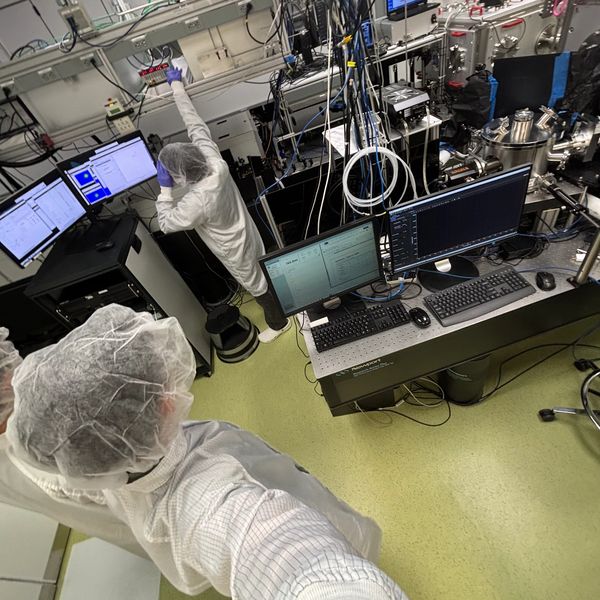 Scientists in protective gear working with advanced lab equipment and computer systems.