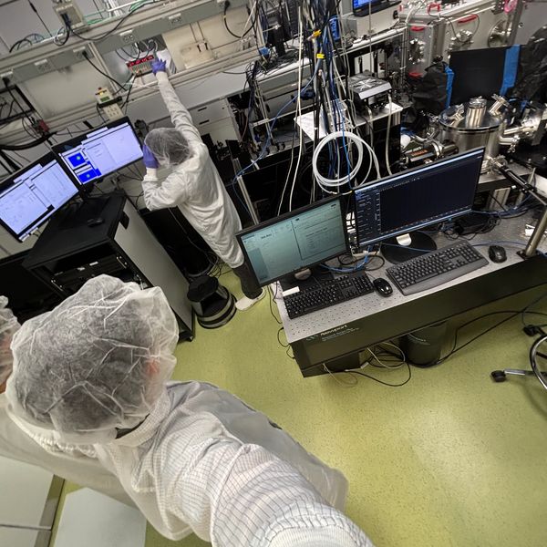 Scientists in protective gear working with advanced lab equipment and computer systems.