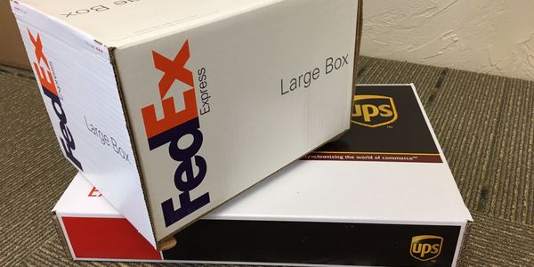 FedEx Express box on top of UPS Express box on shipping counter at Main Street Office in Three Forks