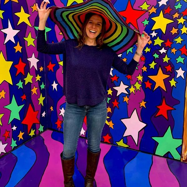 Photo of the owner of the business standing in front of a colorful background