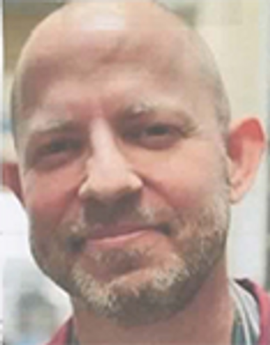 Close-up of a smiling bald man with a beard.