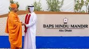 Two men in traditional attire greeting each other in front of BAPS Hindu Mandir, Abu Dhabi.