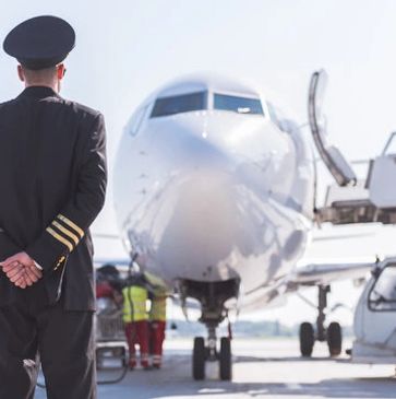 Pilot standing in front of an airplane on the runway.