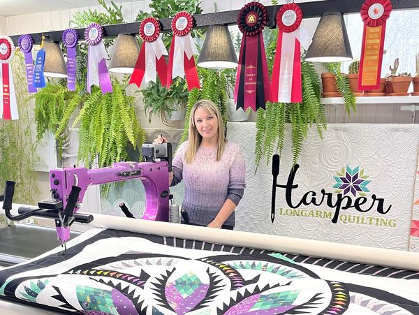 Woman showing achievement ribbons in quilting studio.