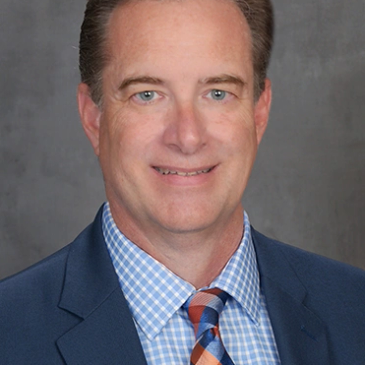 Professional man in a suit and tie smiling at the camera.