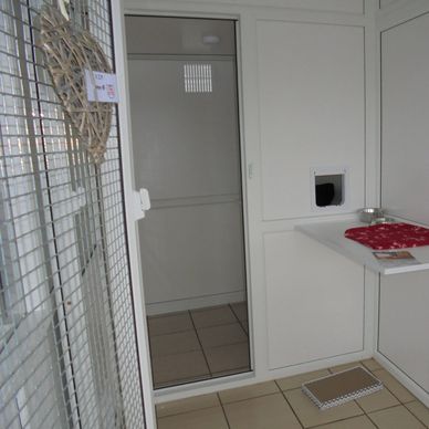 Clean white cleaning supply room with wire mesh door.
