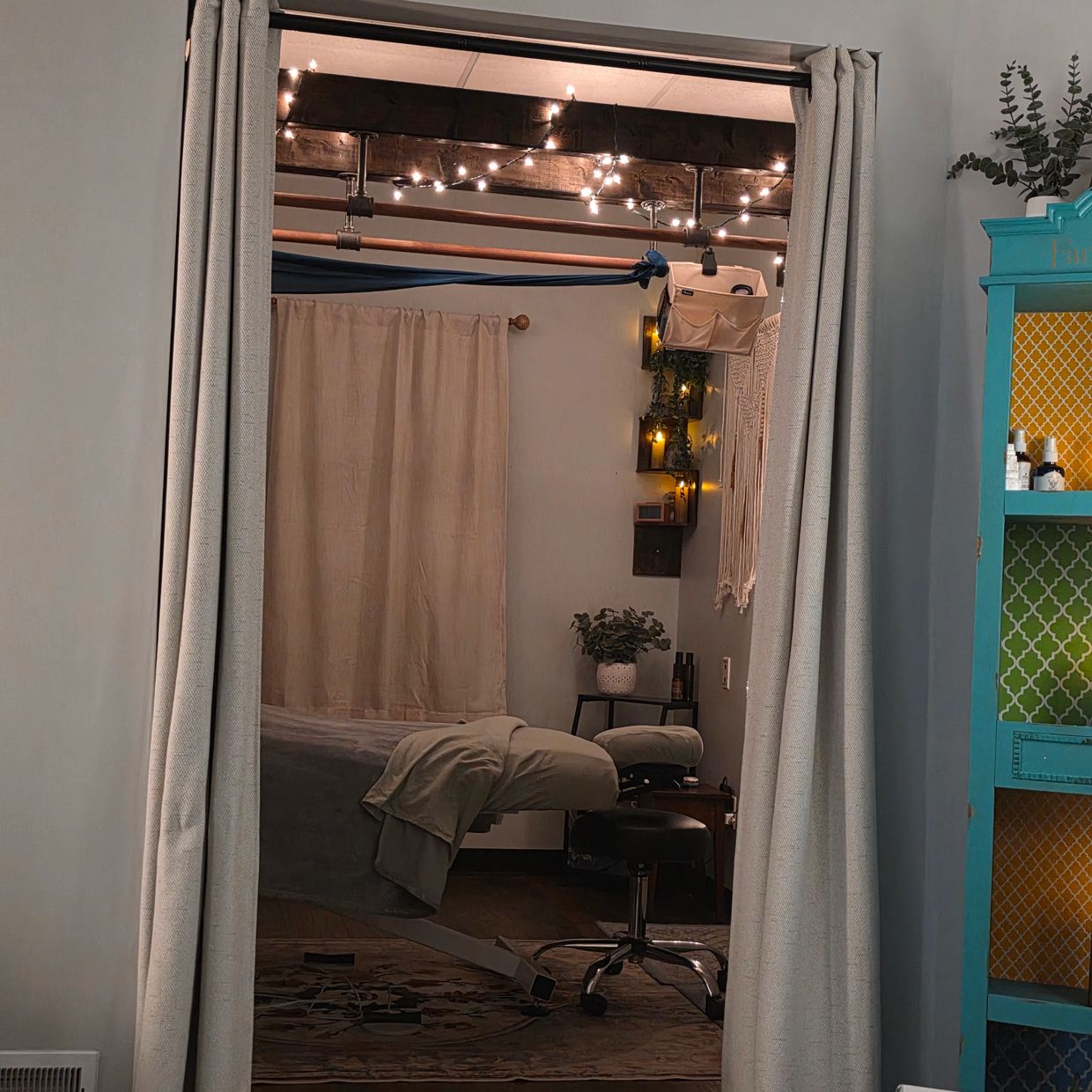 Cozy room with a massage table and string lights.