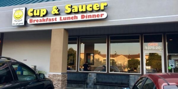 Exterior of Cup &amp; Saucer restaurant with cars parked outside.