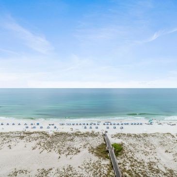A serene beach with blue umbrellas and calm ocean waves under a clear sky.