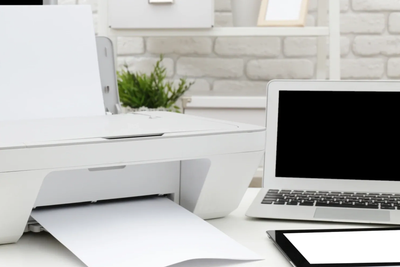 Printer, laptop, and tablet on a white desk.