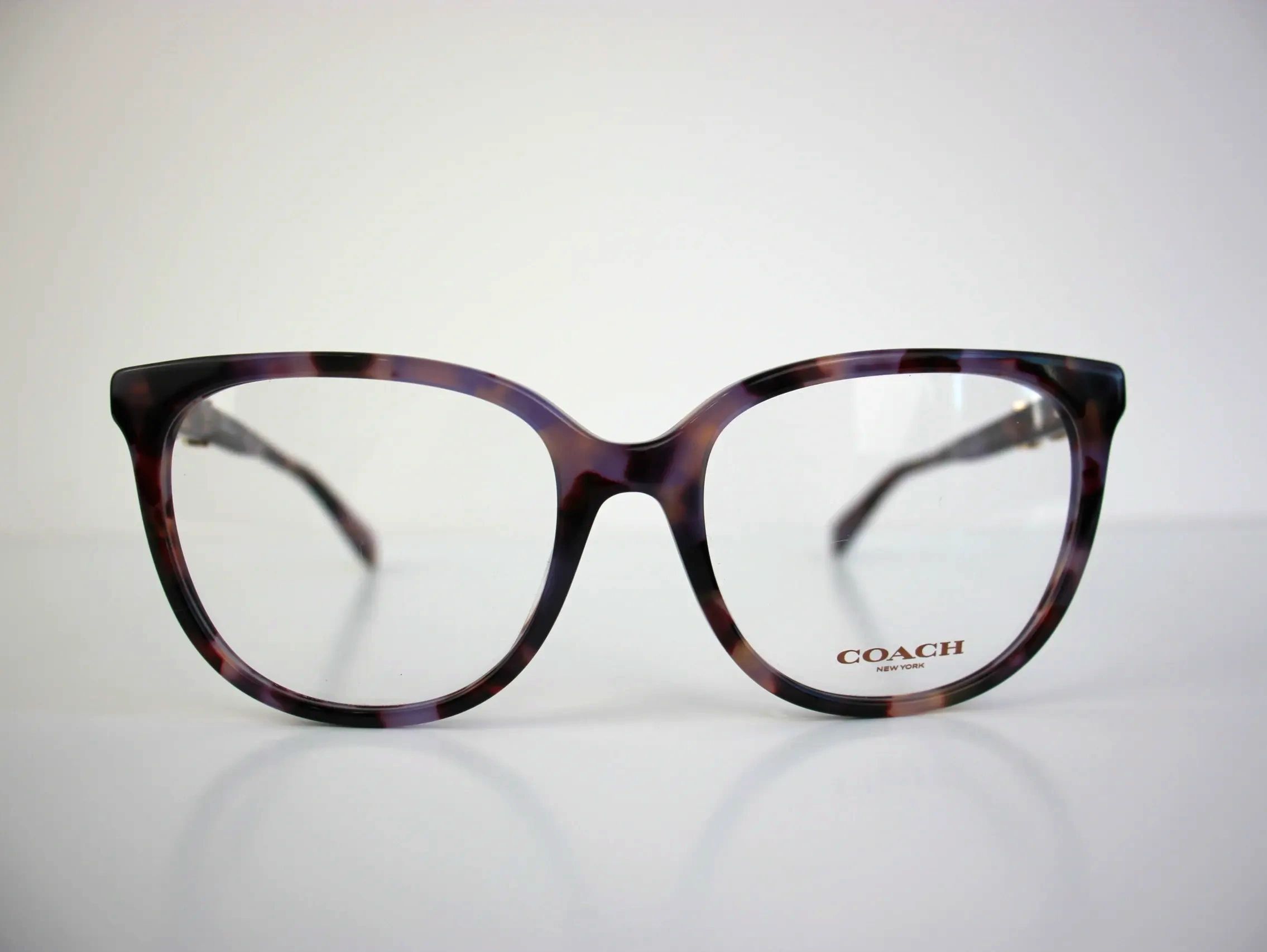Close-up of tortoiseshell Coach eyeglasses on a white background.