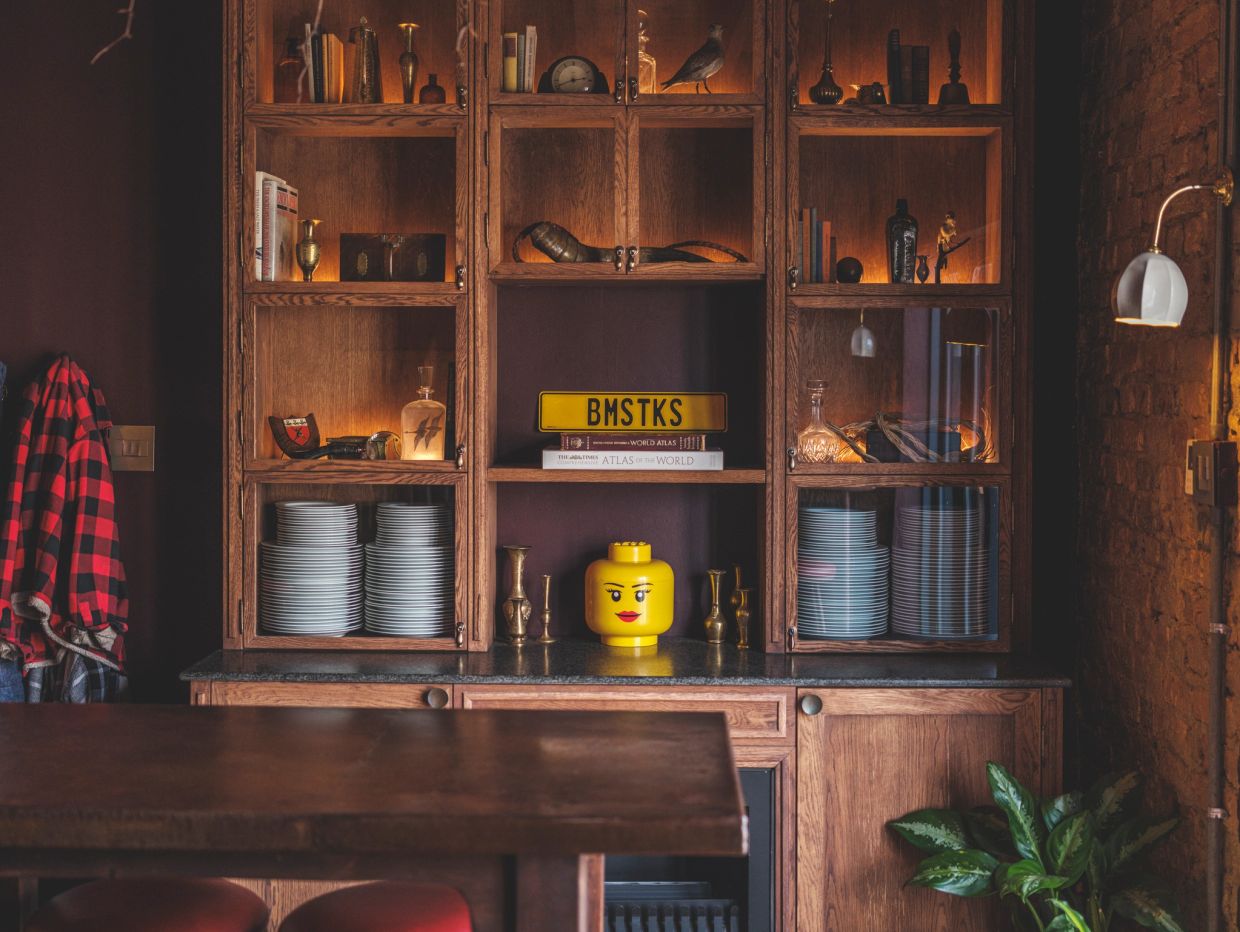 Cozy wooden cabinet with dishes, books, and decorative items including a LEGO head.
