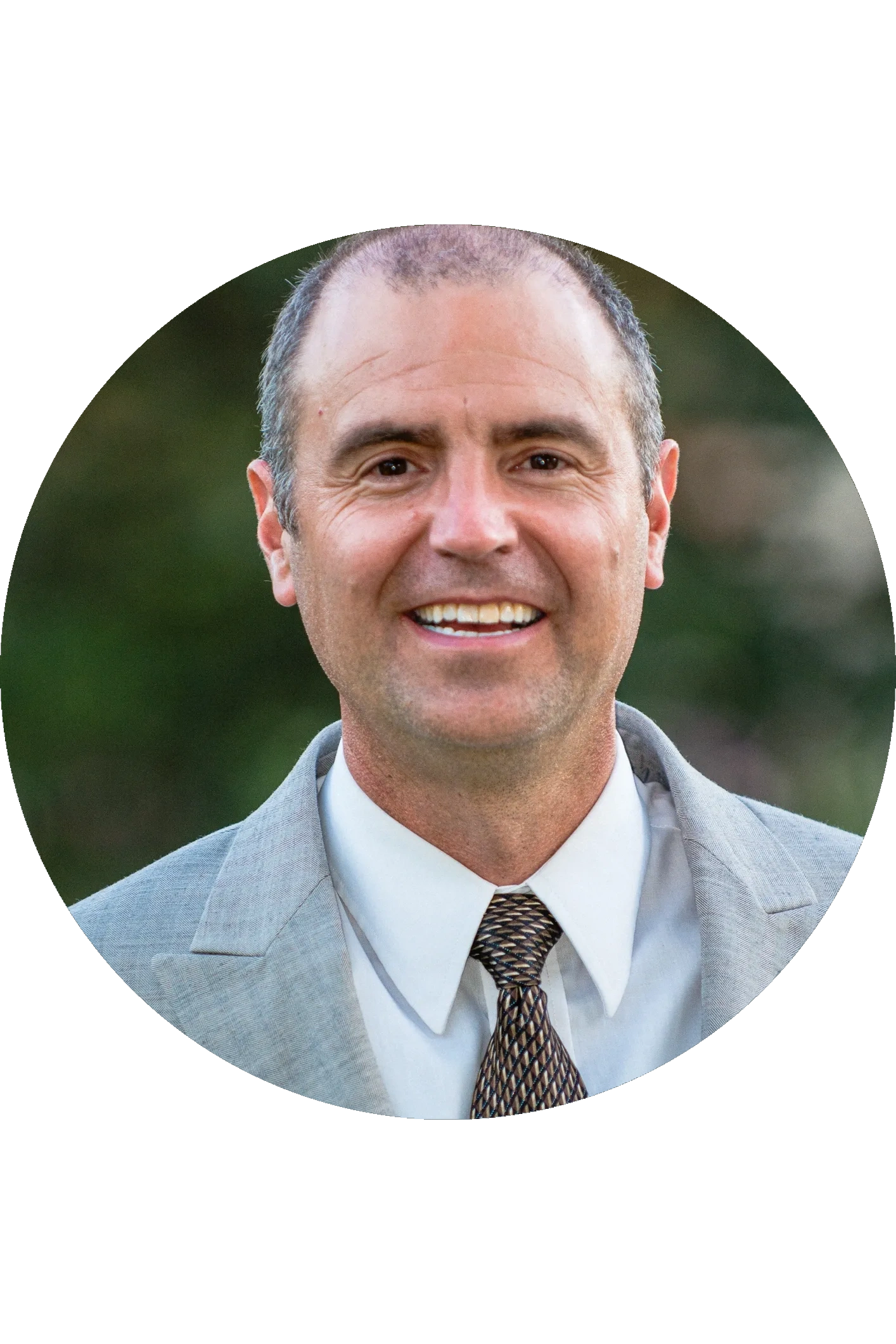Smiling man in a suit and tie outdoors.