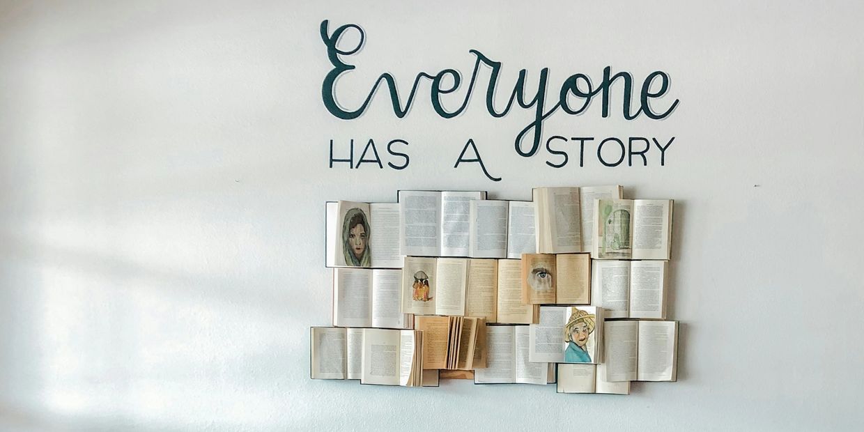 Books on a wall with the phrase 'Everyone has a story' above them.