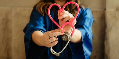 Person holding a stethoscope shaped like a heart.