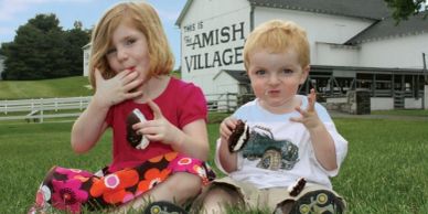 Two young children enjoying cake outside the Amish Village.