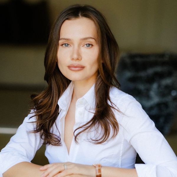 Confident woman with long brown hair wearing a white shirt.