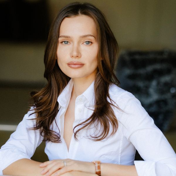 Confident woman with long brown hair wearing a white shirt.