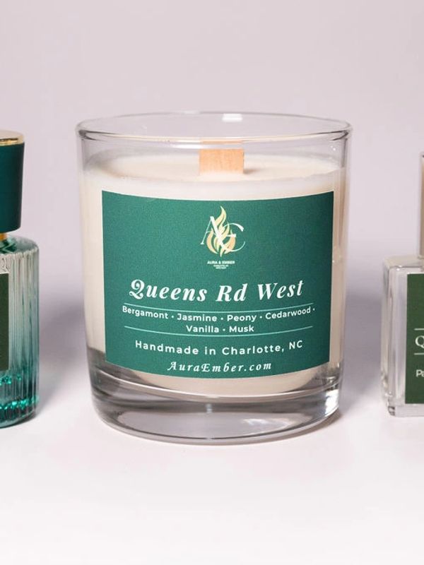 Scented candle labeled Queens Rd West with floral and woody notes.