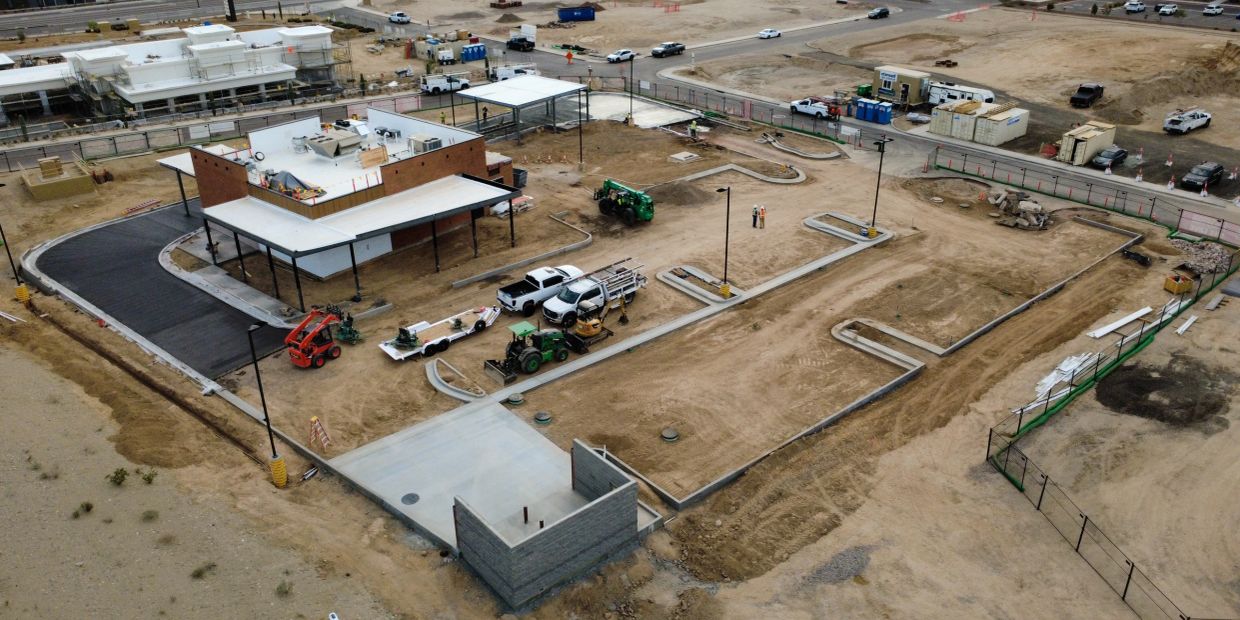 Construction site with partially built structures and equipment on barren land.