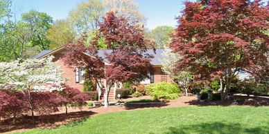 A brick house surrounded by colorful trees and a green lawn.