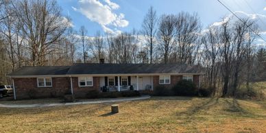 Single-story brick house with a large front yard and bare trees in winter.