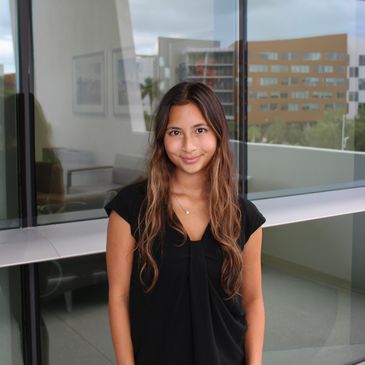 Young woman smiling indoors near a window.
