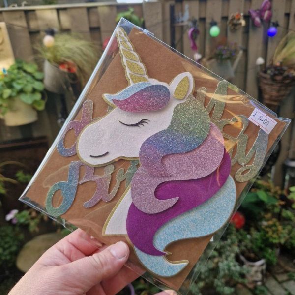Hand holding a glittery unicorn birthday card.
