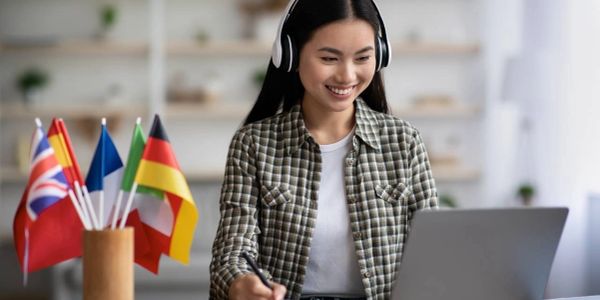 Junge Frau lernt online mit Kopfhörern vor Laptop.