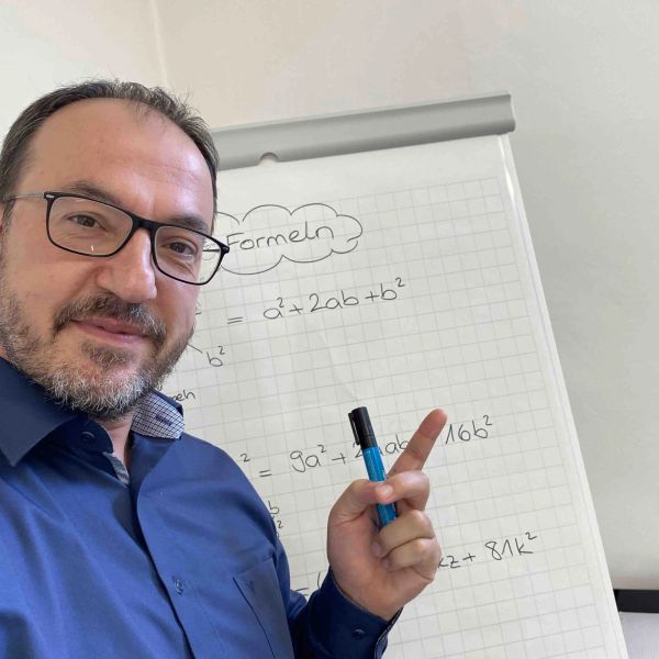 Mann zeigt auf Formeln auf einem Flipchart.
