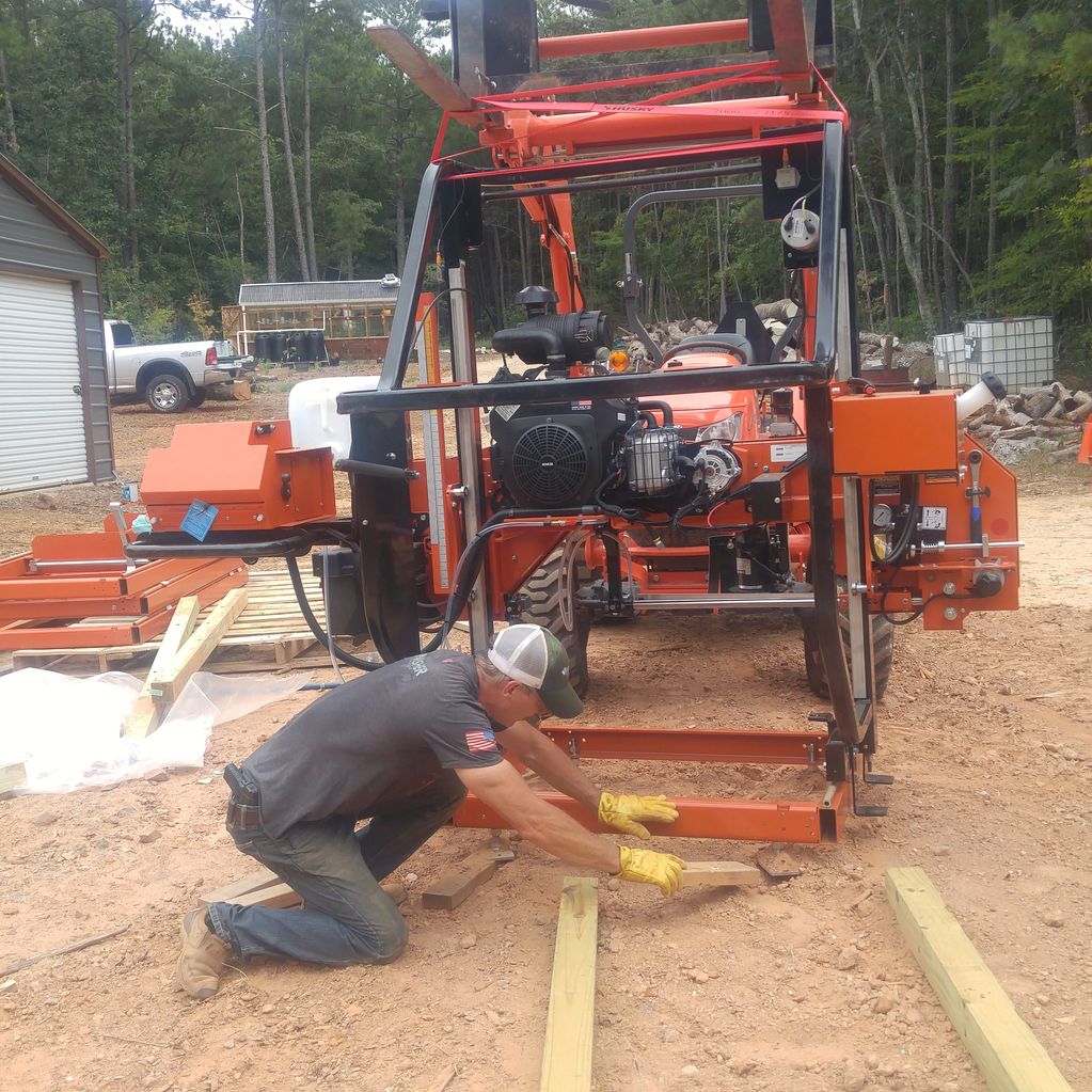 man leveling ground
kubuta tractor lifting Wood-Mizer with forklifts
installing Wood-Mizer