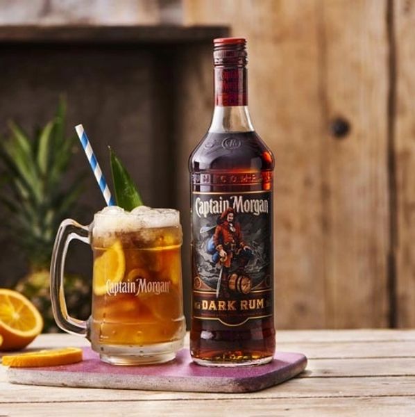 A bottle of Captain Morgan Dark Rum with a glass of rum cocktail.