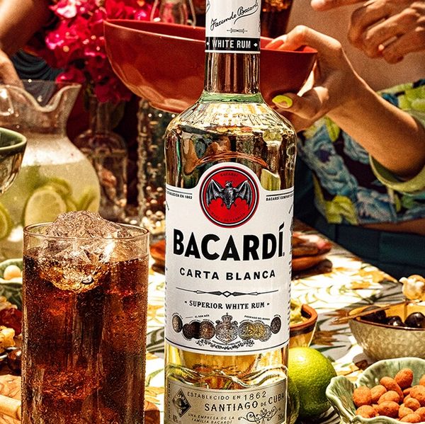 Bottle of Bacardi Carta Blanca rum with a glass of iced drink on a festive table.