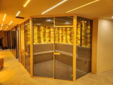 Modern sauna room with warm lighting and glass doors.