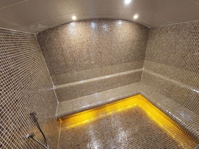Luxurious steam room with mosaic tiles and warm ambient lighting.