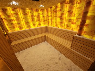 Cozy salt room with wooden benches and soft glowing amber walls.