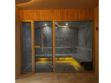 Modern sauna room with warm yellow lighting and tiled interior.