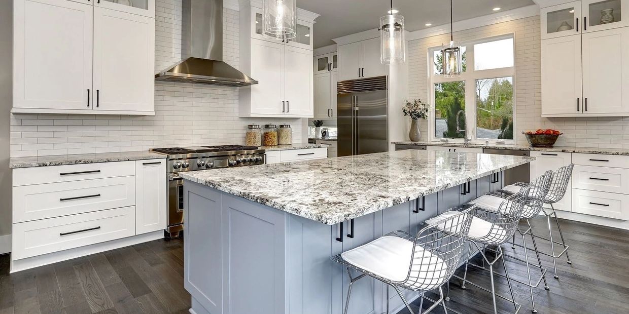 White kitchen with silver accents and white and gray countertop.