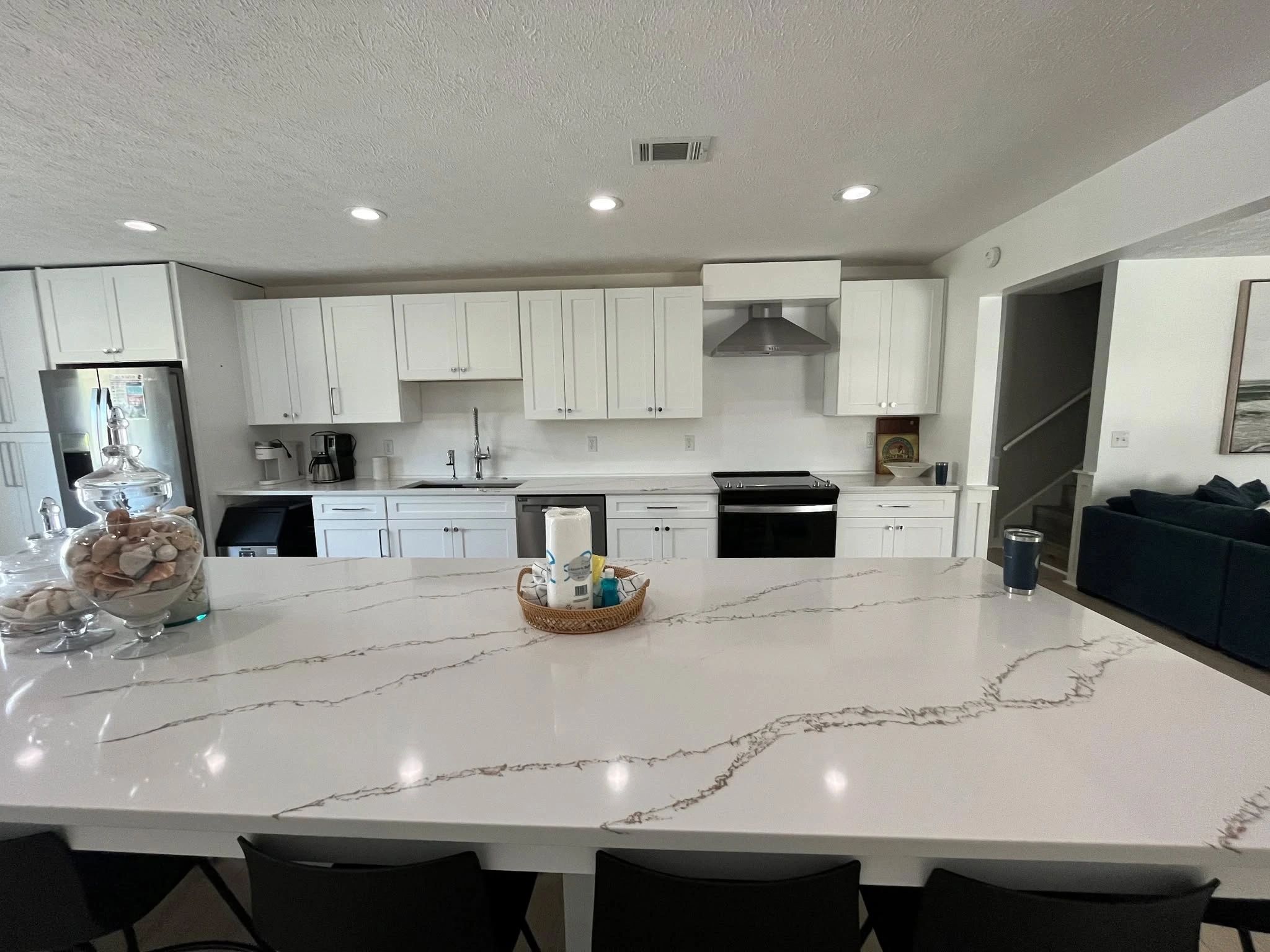 Modern kitchen with white cabinets and marble countertop island.