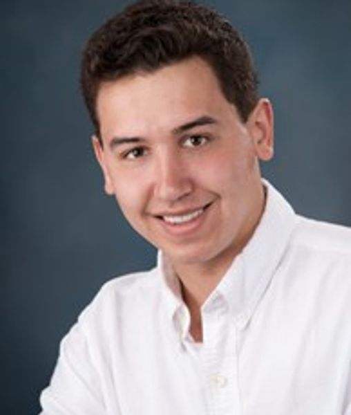 Young man smiling in white shirt.