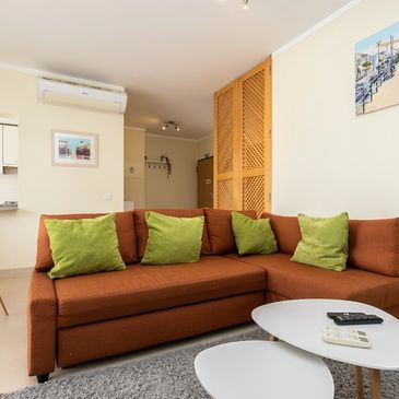 Modern living room with brown sofa and green cushions.