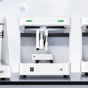 Three white automated laboratory machines with robotic arms.